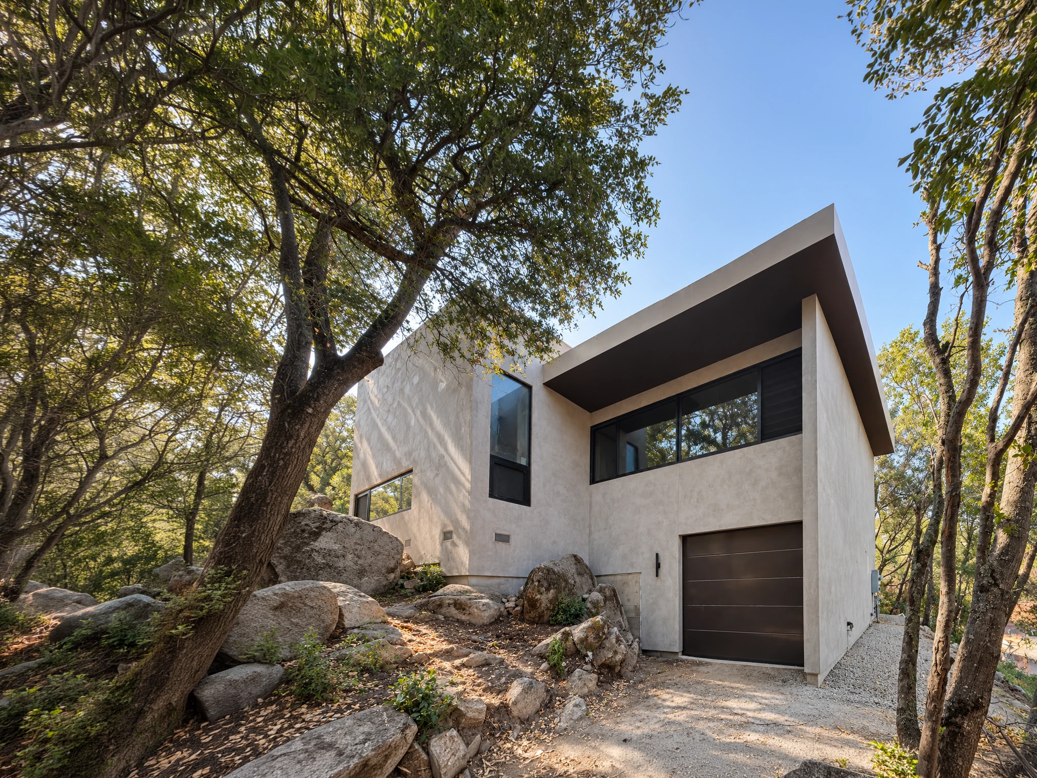 Cabin Black viewed from the driveway, with garage and windows framed by mature trees