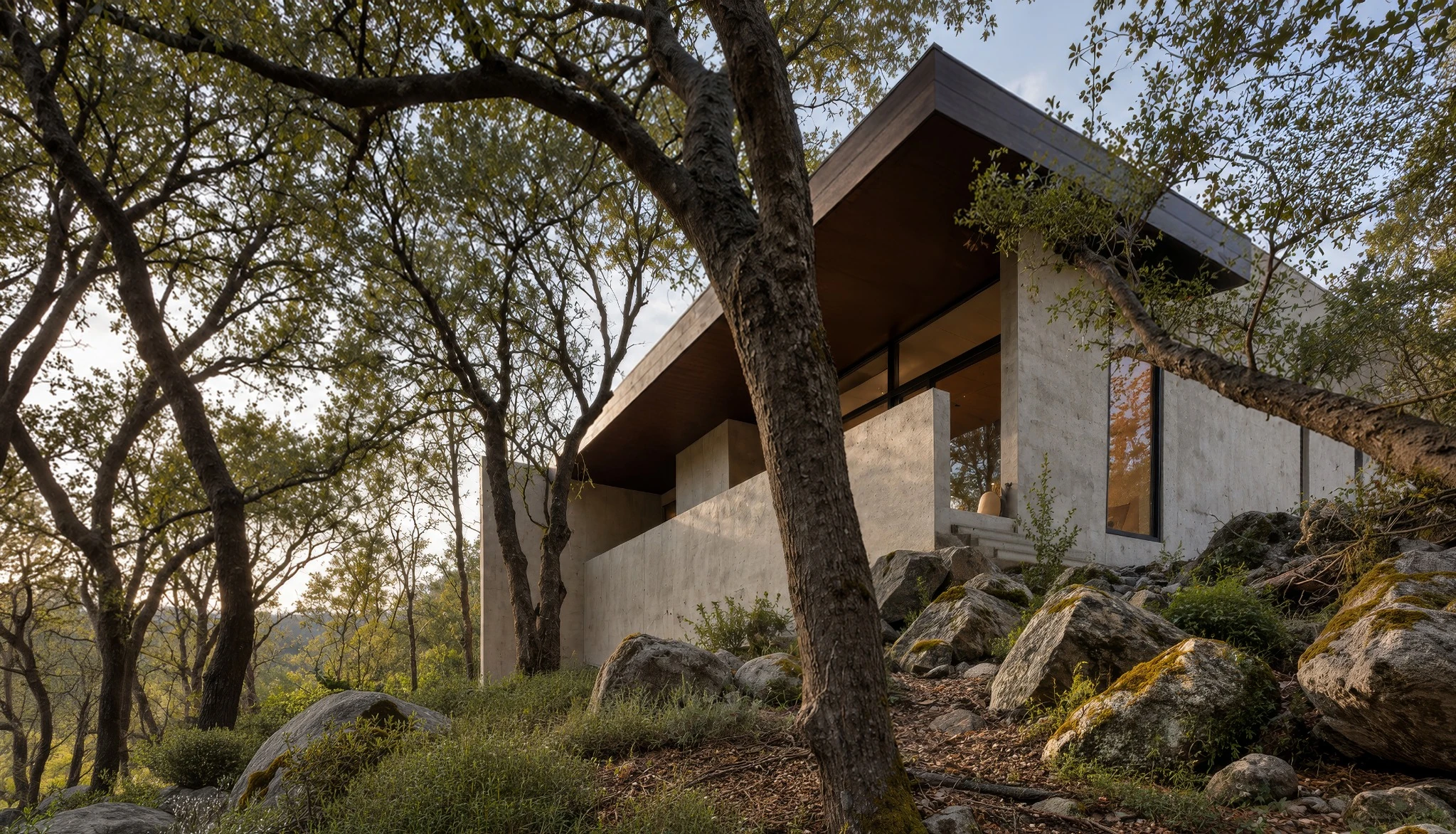 Rear terrace and deep roof overhang of Cabin Black among trees and boulders